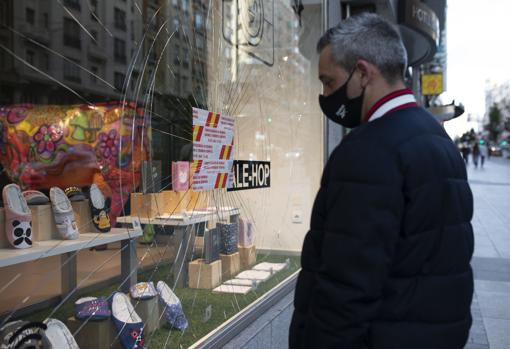 Un hombre mira el escapate roto de una tienda en Gran Vía