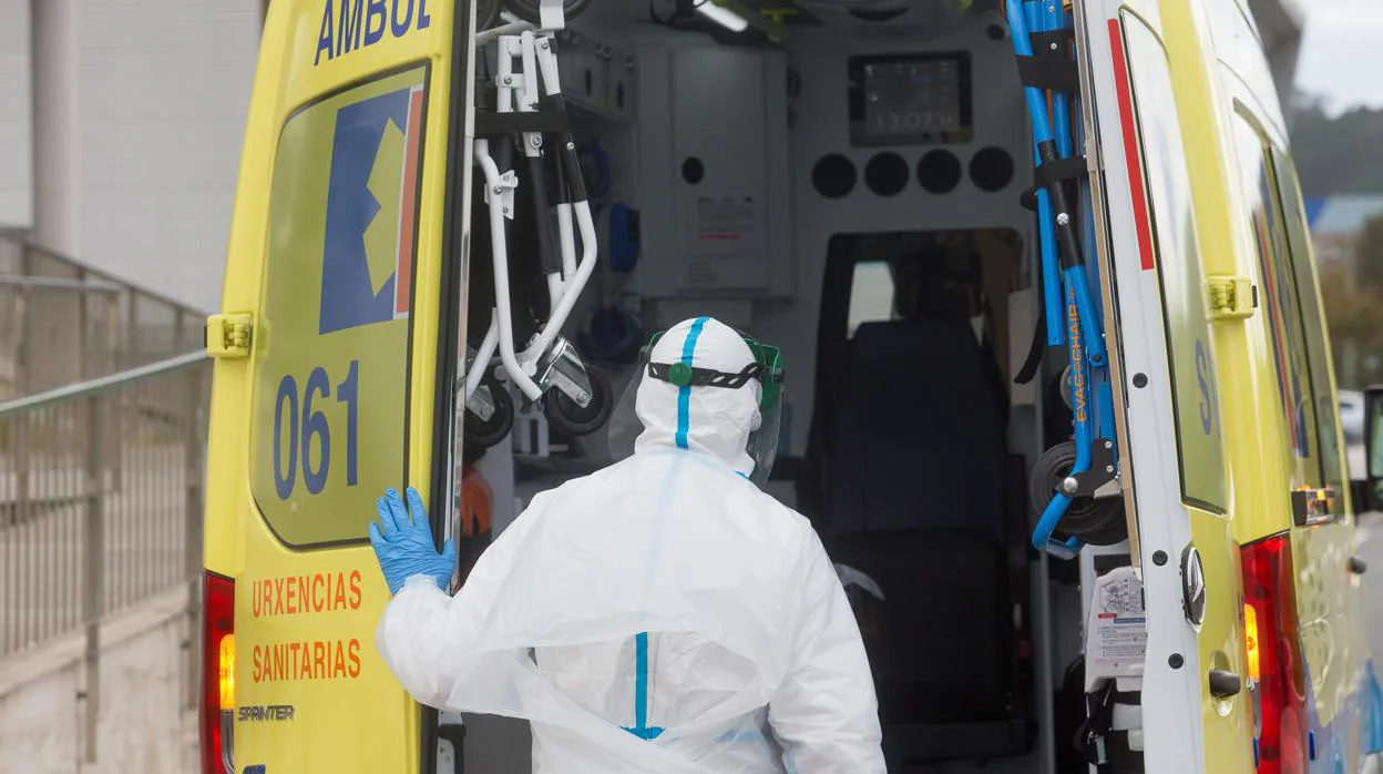 Un trabajador sanitario totalmente protegido cierra la puerta de una ambulancia