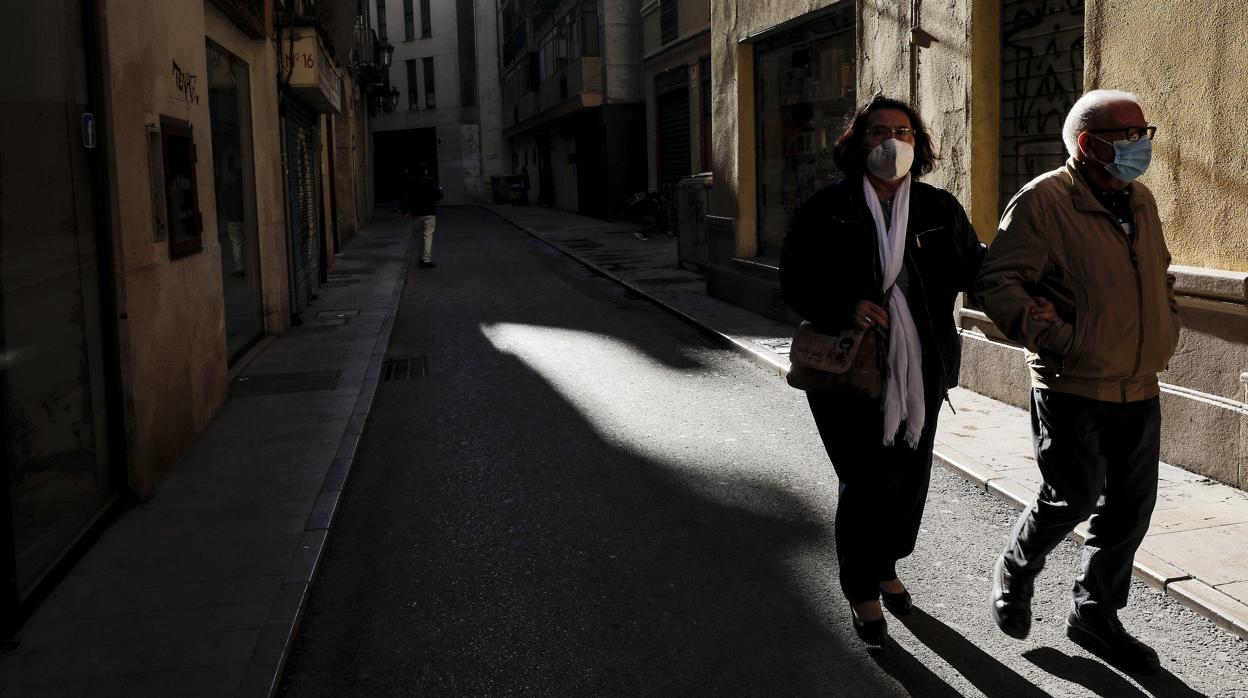 Imagen de dos personas paseando por Valencia con mascarilla por el coronavirus