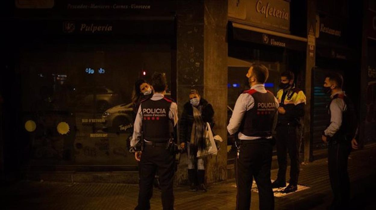 Agentes de los Mossos d'Esquadra paran a una persona en un control durante el toque de queda