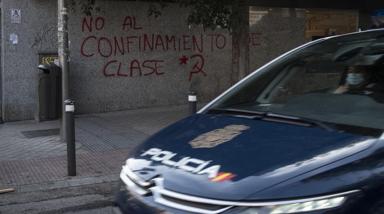 Un coche de Policía circula delante de una pintada