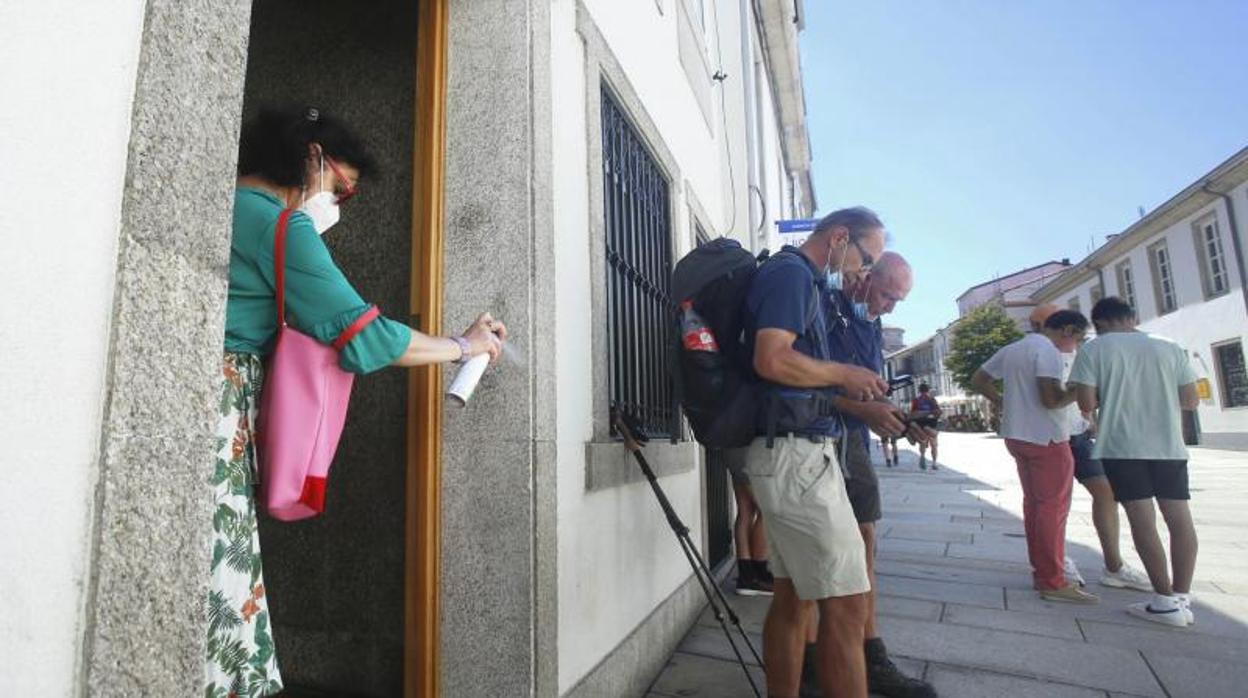 Una mujer desinfecta la entrada de su casa, ante el centro de recepción de peregrinos en Santiago