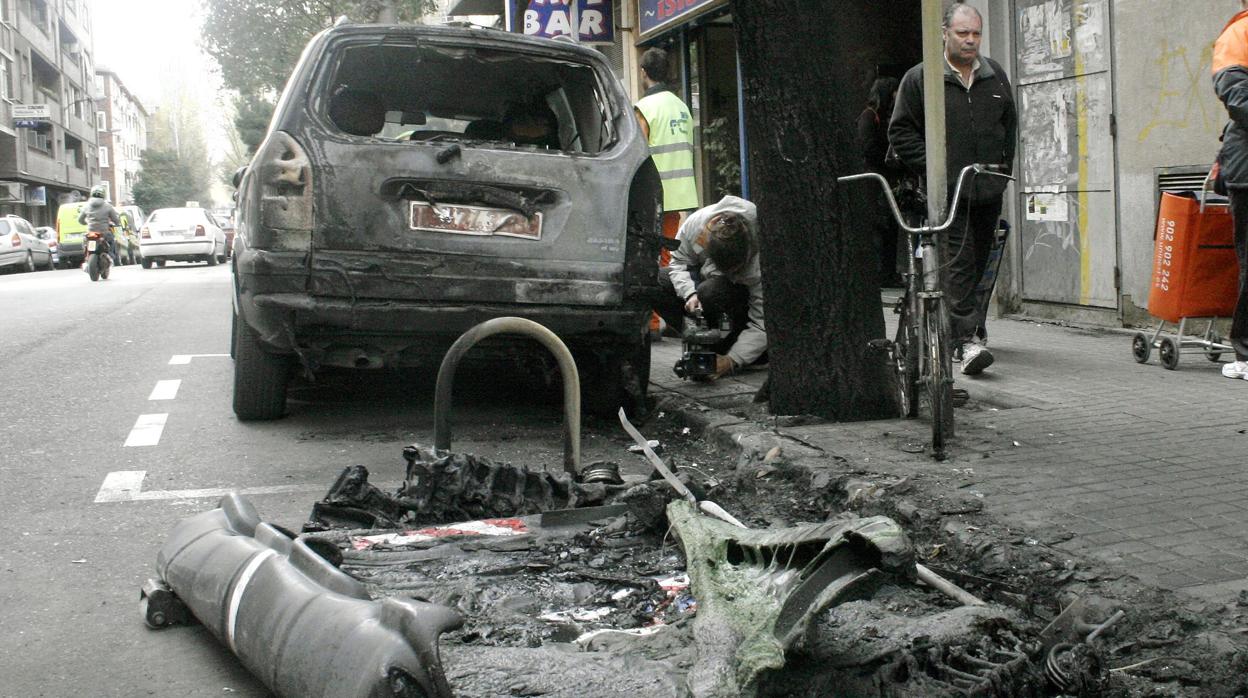 Imagen de archivo de un coche calcinado por la quema de un contenedor en una calle de Zaragoza