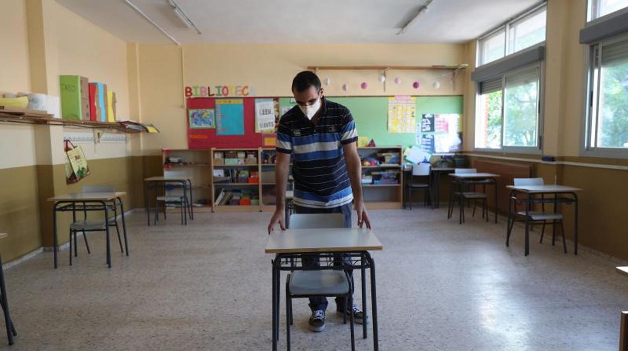 Un profesor coloca las mesas para mantener la distancia entre los alumnos en un colegio madrileño