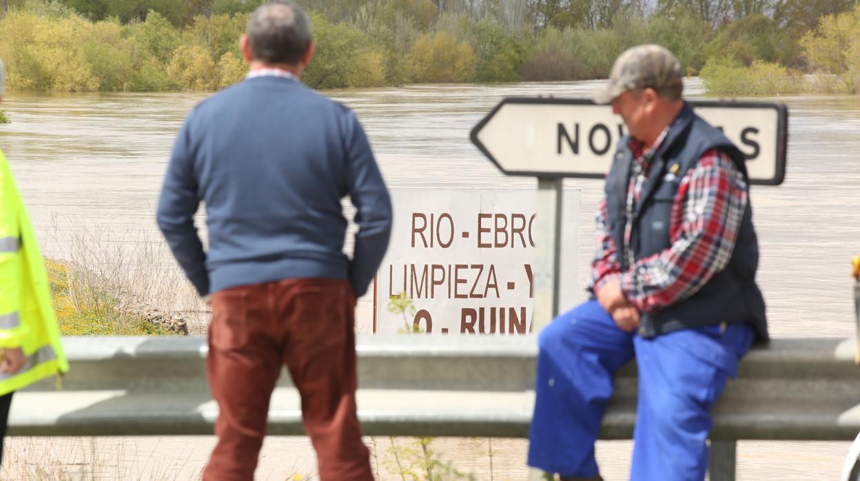 Dos lugareños observan en Novillas (Zaragoza) el desbordado cauce del Ebro durante una riada