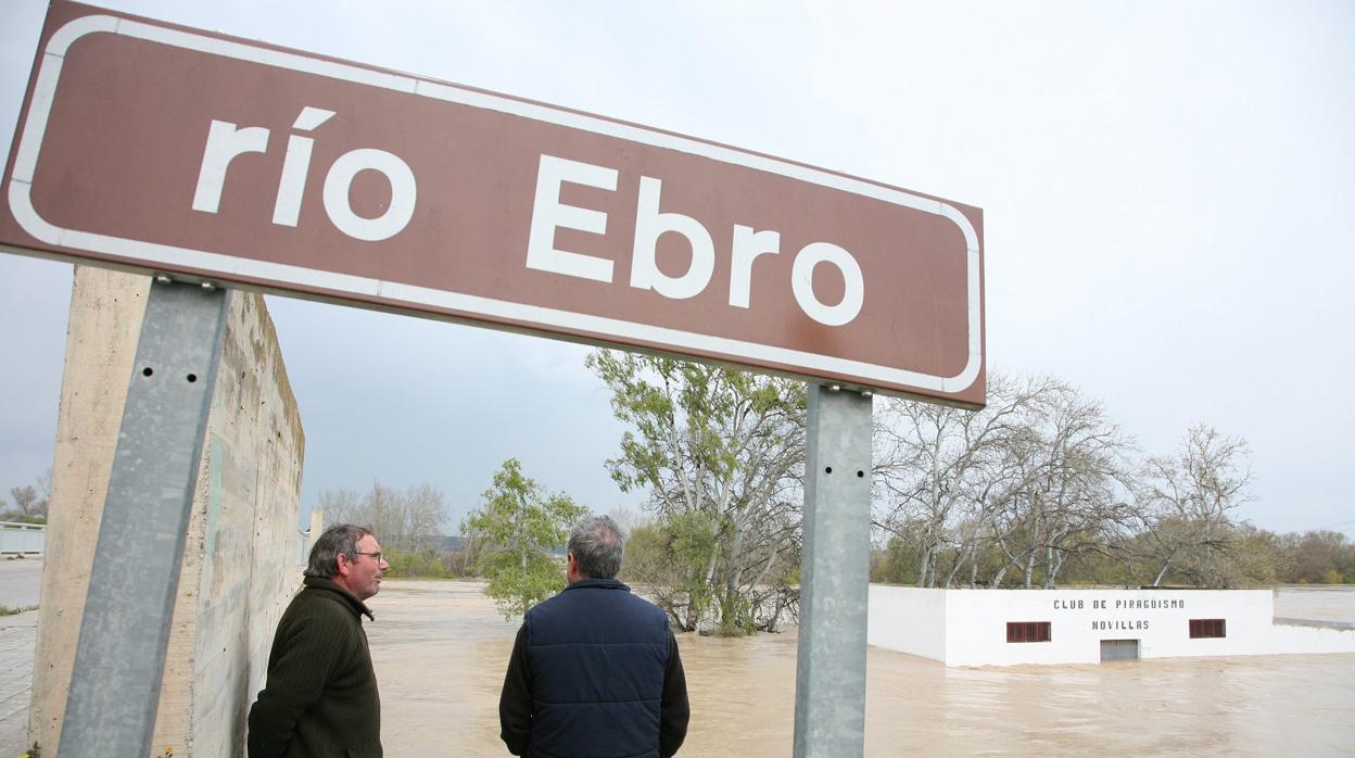 Dos lugareños miran el desbocado cauce del Ebro a su paso por Novillas (Zaragoza) en una de las riadas que sufren los pueblos ribereños de forma cada vez más recurrente