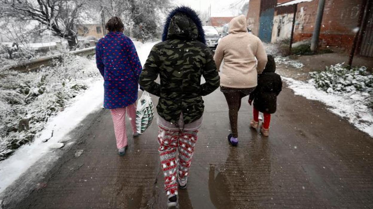 Varios residentes del asentamiento de la Cañada Real caminan bajo la nieve este jueves