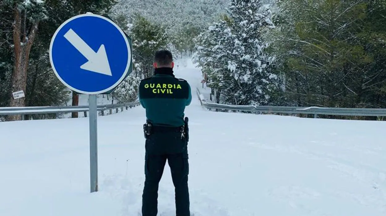 Un agente observa una carretera de la turística zona de Nuévalos (Zaragoza) totalmente cubierta por la nieve del temporal Filomena