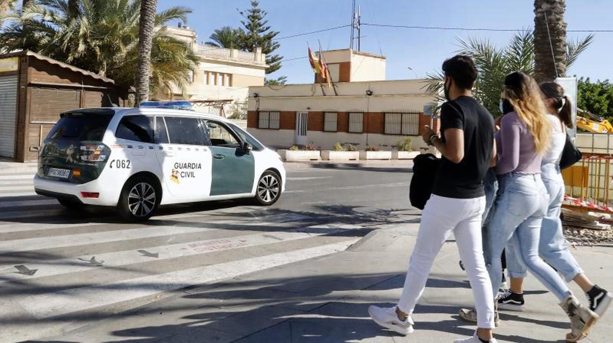 Adolescentes pasan junto a un coche de la Guardia Civil en Torrevieja