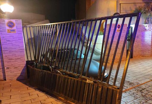 El coche accidentado contra la puerta metálica