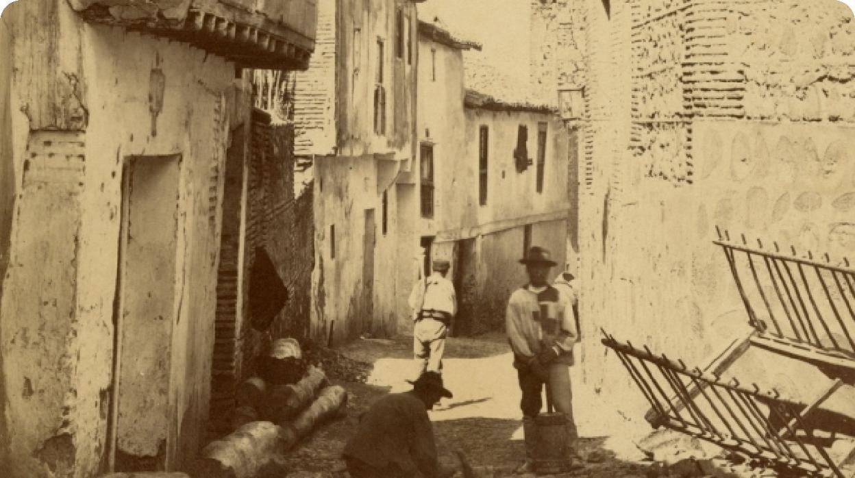 Dos empedradores trabajan con alcotana y pisón de mano, en la actual calle de Alfonso VI, hacia 1880. A la derecha, el muro de la iglesia parroquial de Santiago el Mayor. Fotografía de Casiano Alguacil. Archivo Municipal de Toledo. Colección Luis Alba