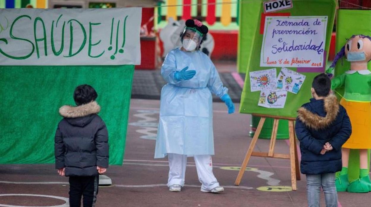 Una sanitaria junto a dos niños en uno de los cribados realizados en Galicia