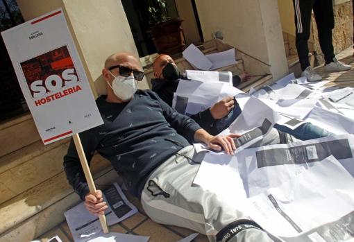 Dos manifestantes cubiertos de facturas, en un gesto simbólico de su situación económica