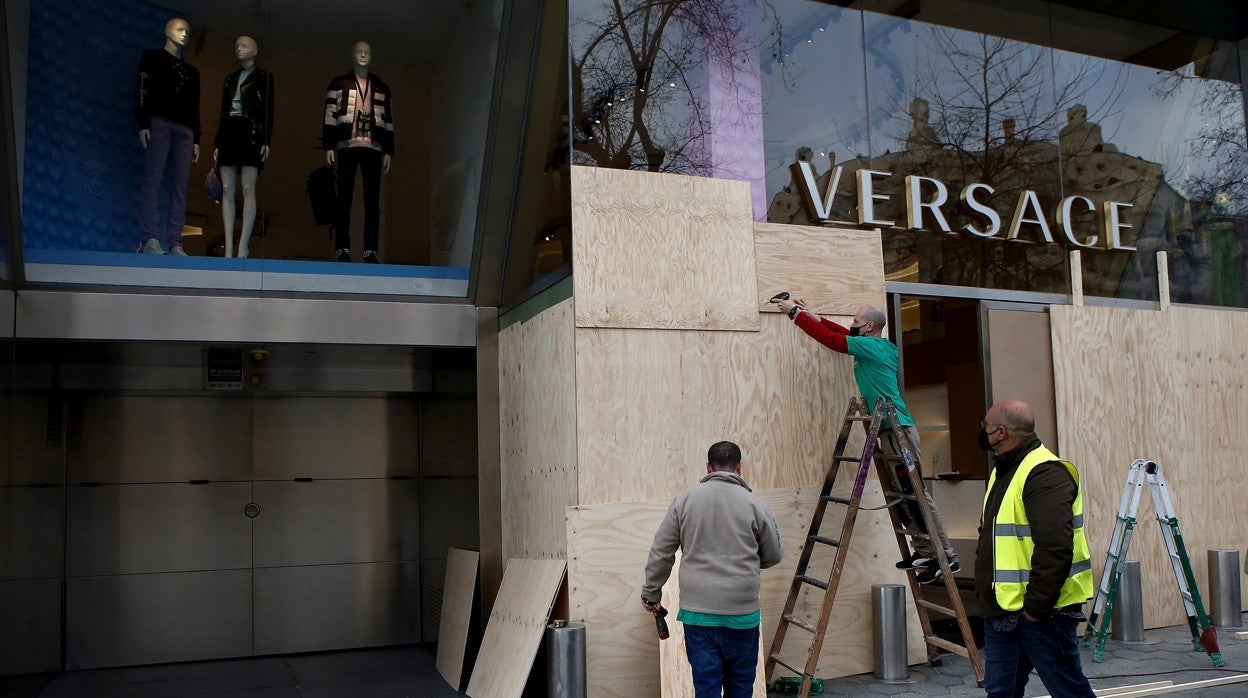 Operarios protegen el escaparate de uno de los comercios saqueados