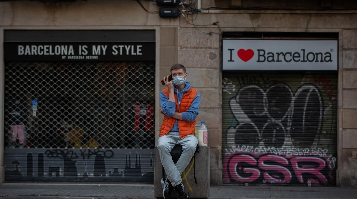 Un hombre escucha a su teléfono móvil frente a dos tiendas turísticas en Barcelona