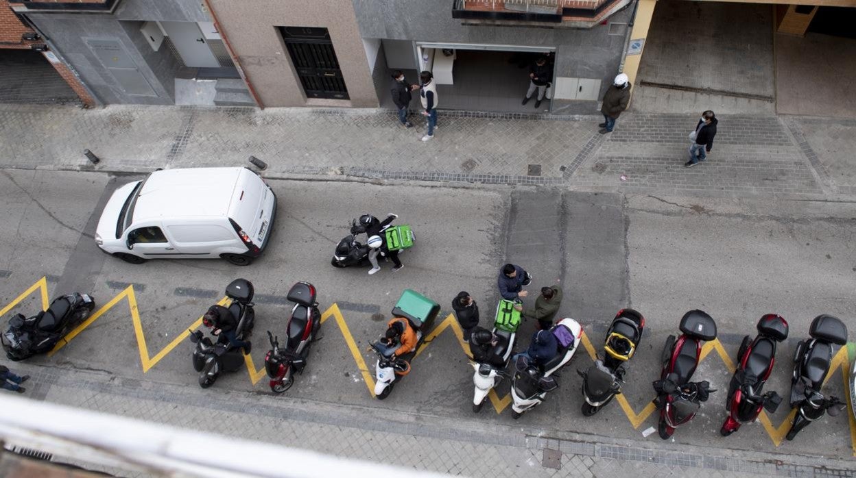 Una docena de repartidores esperan los pedidos frente a la cocina industrial de Tetuán