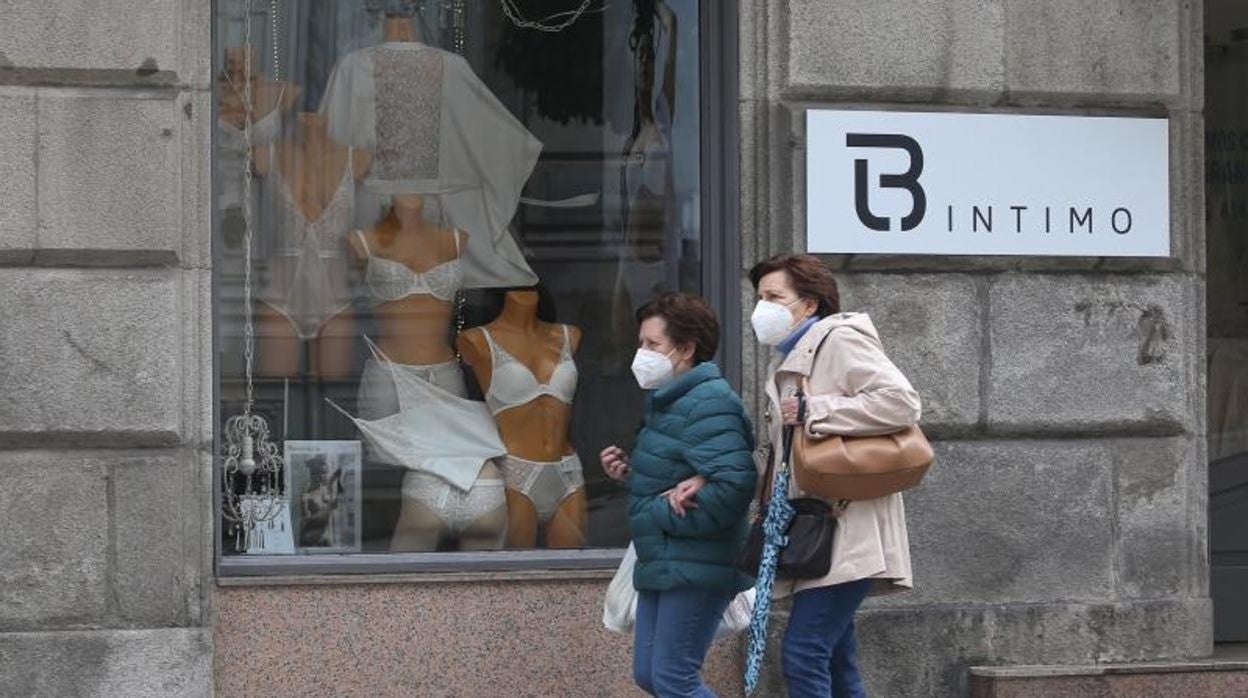 Dos transeúntes caminan ante un comercio gallego