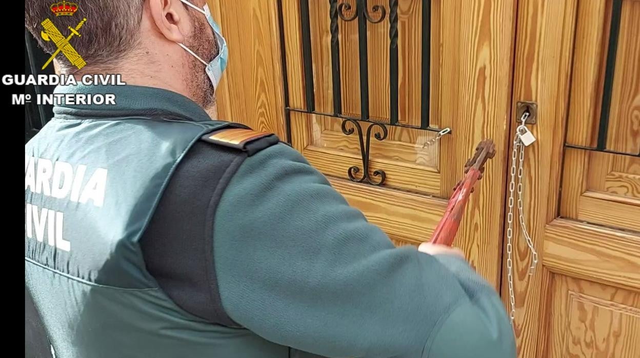 Un guardia civil abre la puerta de una vivienda okupada, durante la operación