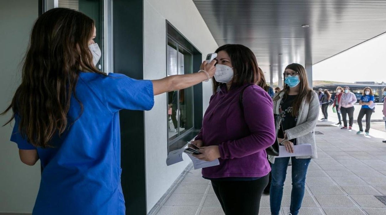 Una sanitaria toma la temperatura a una docente a las puertas del hospital de Toledo