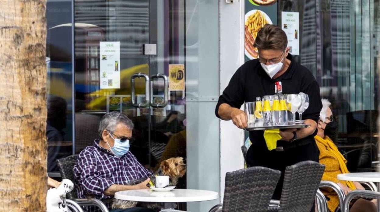 Un camarero sirve una consumición a un cliente en una cafetería en Benidorm, durante esta Semana Santa