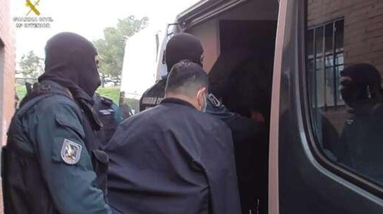 Los agentes conducen a uno de los arrestados al furgón