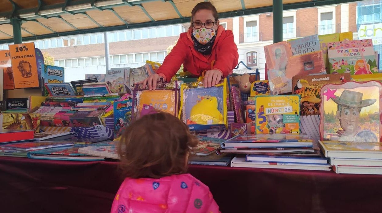 La librera Cristina Bustos enseña dos cuentos a una niña en Valladolid