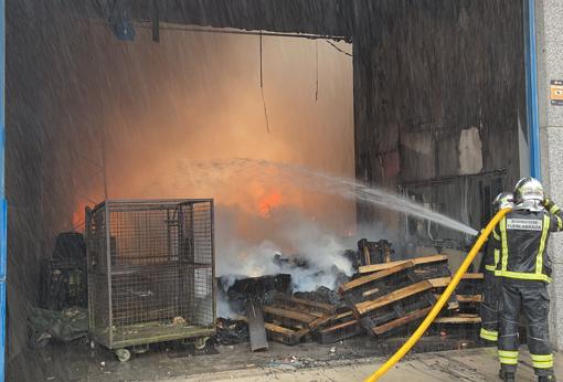 Los bomberos atacan el fuego en el interior de la nave incendiada, en Fuenlabrada