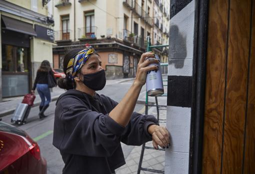 Paloma pinta la fachada del restobar Raíces, en la calle Torrecilla del Leal