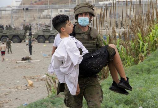 Un soldado del Ejército de Tierra ayuda a un inmigrante que ha logrado cruzar uno de los espigones fronterizos de Ceuta