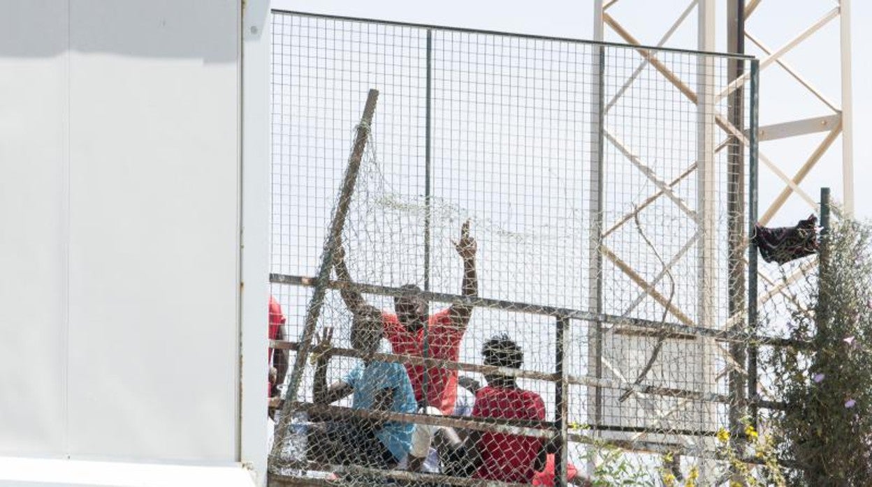 Varios inmigrantes, fotografiados ayer detrás de una valla en la Ciudad del Fútbol del Altos del Real en Melilla