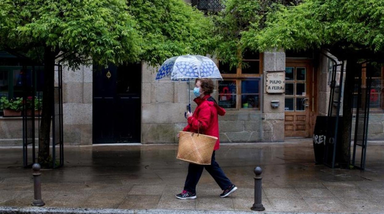 Una mujer se protege de la lluvia en O Carballiño