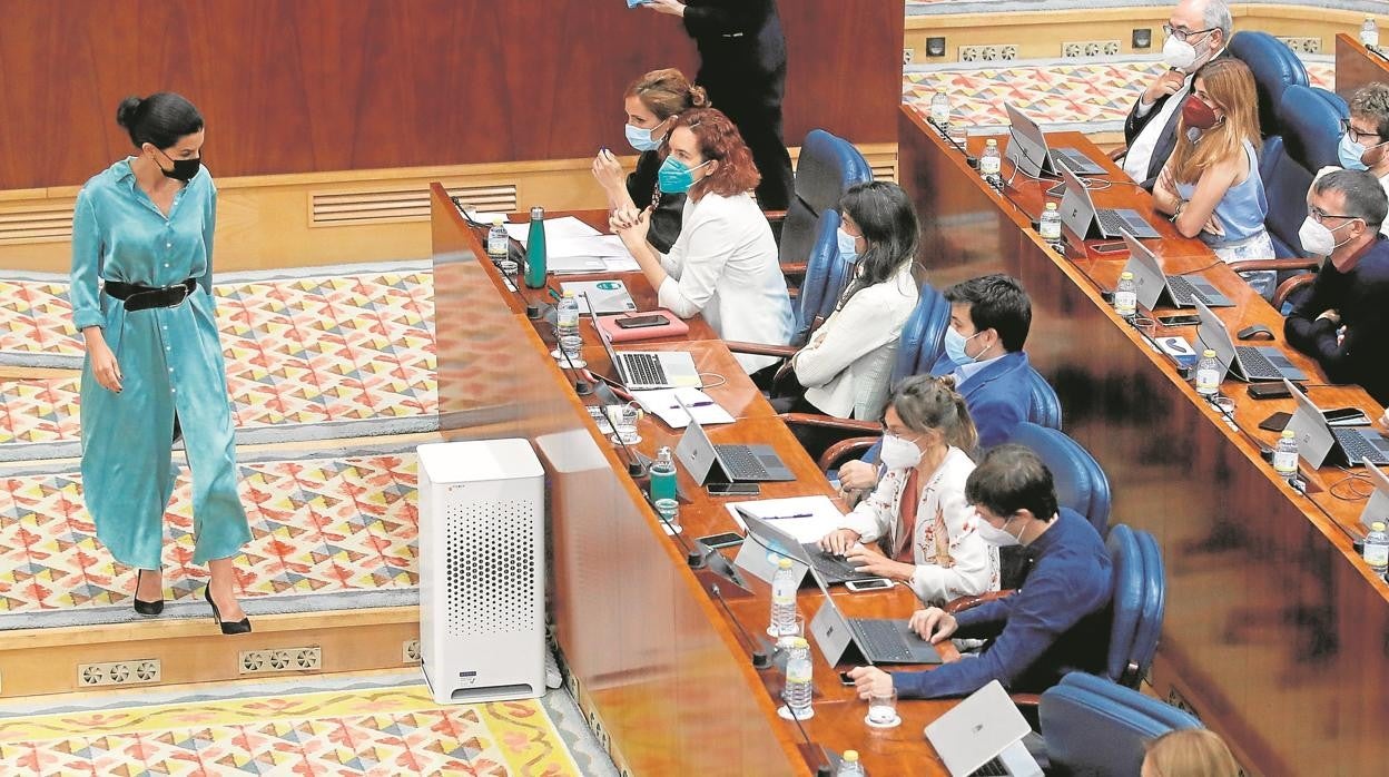 Rocío Monasterio (Vox) se dirige a su escaño ante la mirada de Mónica García (Más Madrid)