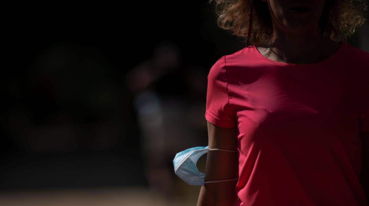 Una mujer pasea con la mascarilla en el brazo por una calle de Orense