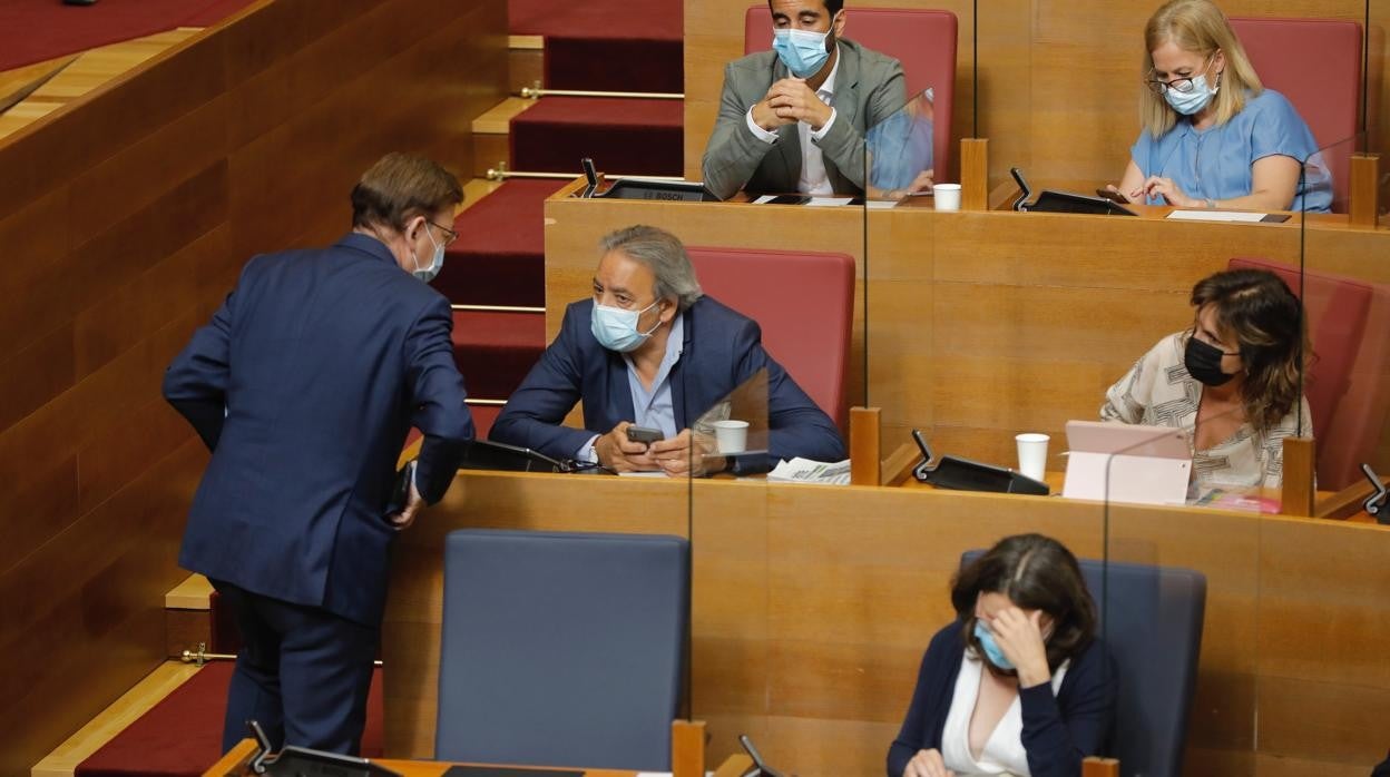 Ximo Puig conversa con Manolo Mata mientras Oltra se mantiene en su escaño en una imagen tomads este jueves en las Cortes Valencianas