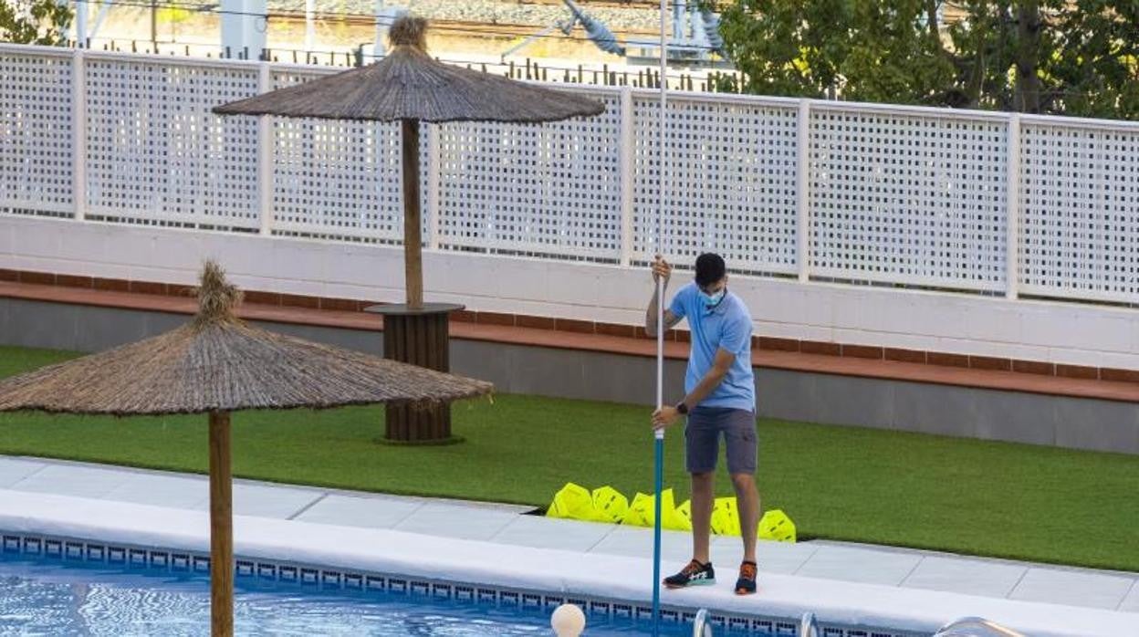 Un hombre se encarga del mantenimiento de una piscina en una urbanización de Alicante