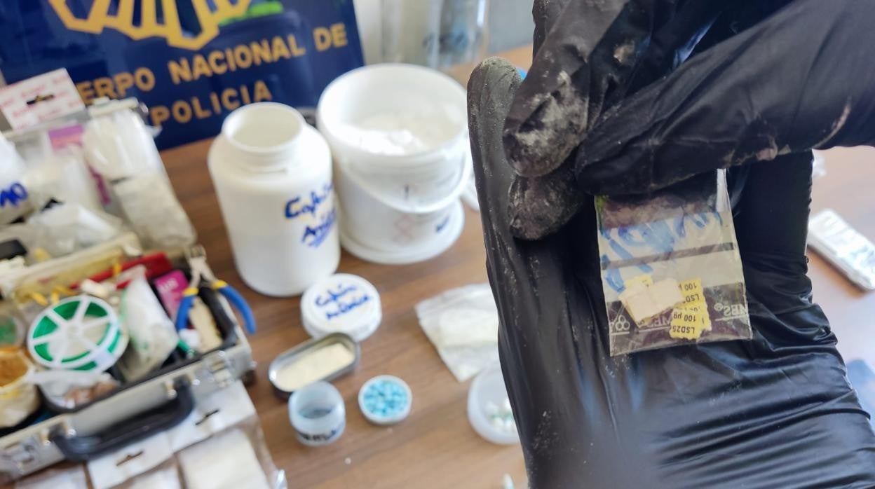 Un policía nacional provisto de guantes muestra uno de los múltiples tipos de drogas que se vendían en el piso