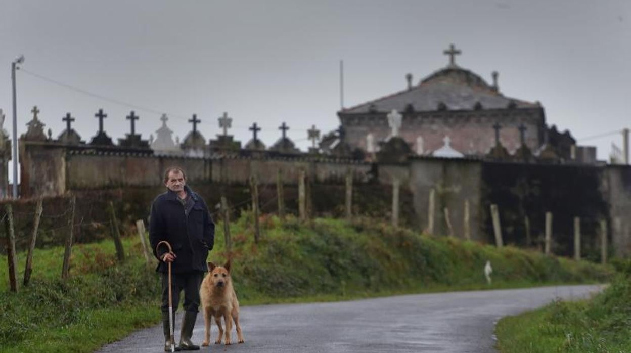 Alfonso y su perro René posan delante del cementerio de la parroquia, en Riveras del Sor, Mañón, La Coruña