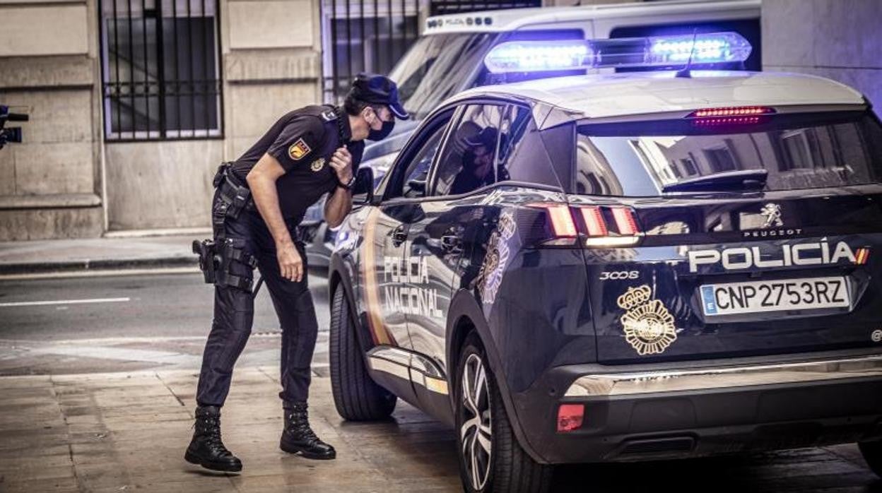 Un agente de la Policía Nacional, junto a una patrulla