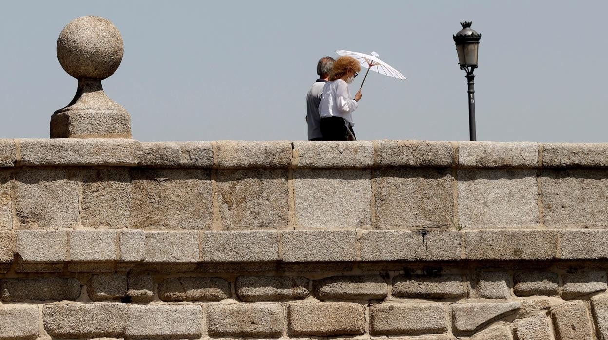 Una mujer se protege del sol con una sombrilla mientras pasea cerca de Madrid Río