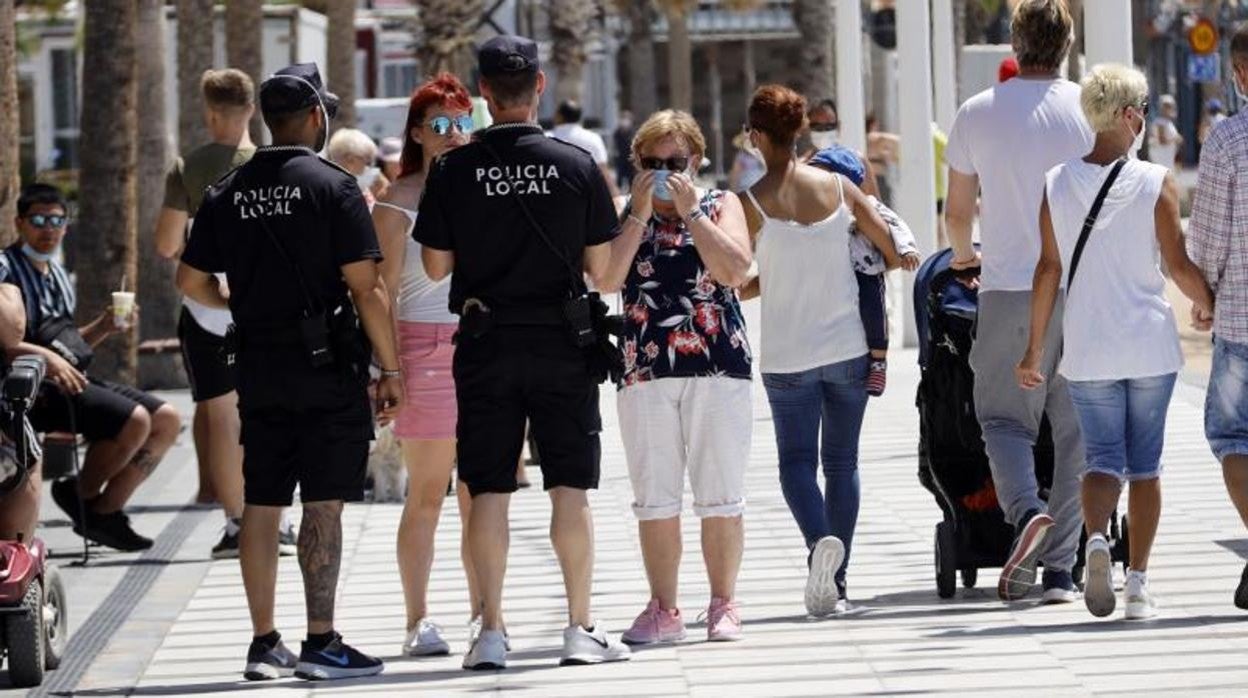 Dos policías locales de Benidorm informando a unas turistas junto a la playa de Levante