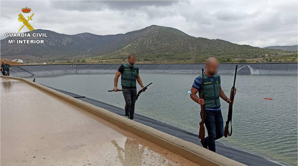 Dos agentes portan cuatro de las escopetas escondidas