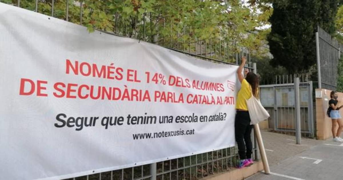 Una joven cuelga una de las pancartas que refuerzan la campaña para impulsar el uso del catalán