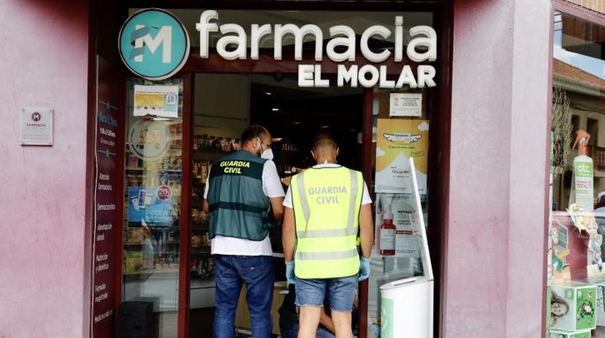 Dos agentes de la Guardia Civil investigan en la puerta de la farmacia, donde se ha producido uno de los apuñalamientos