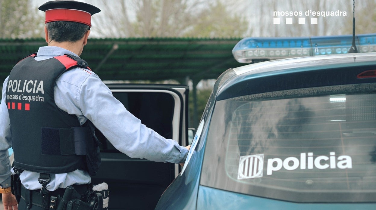 Un agente de los Mossos junto a un coche patrulla