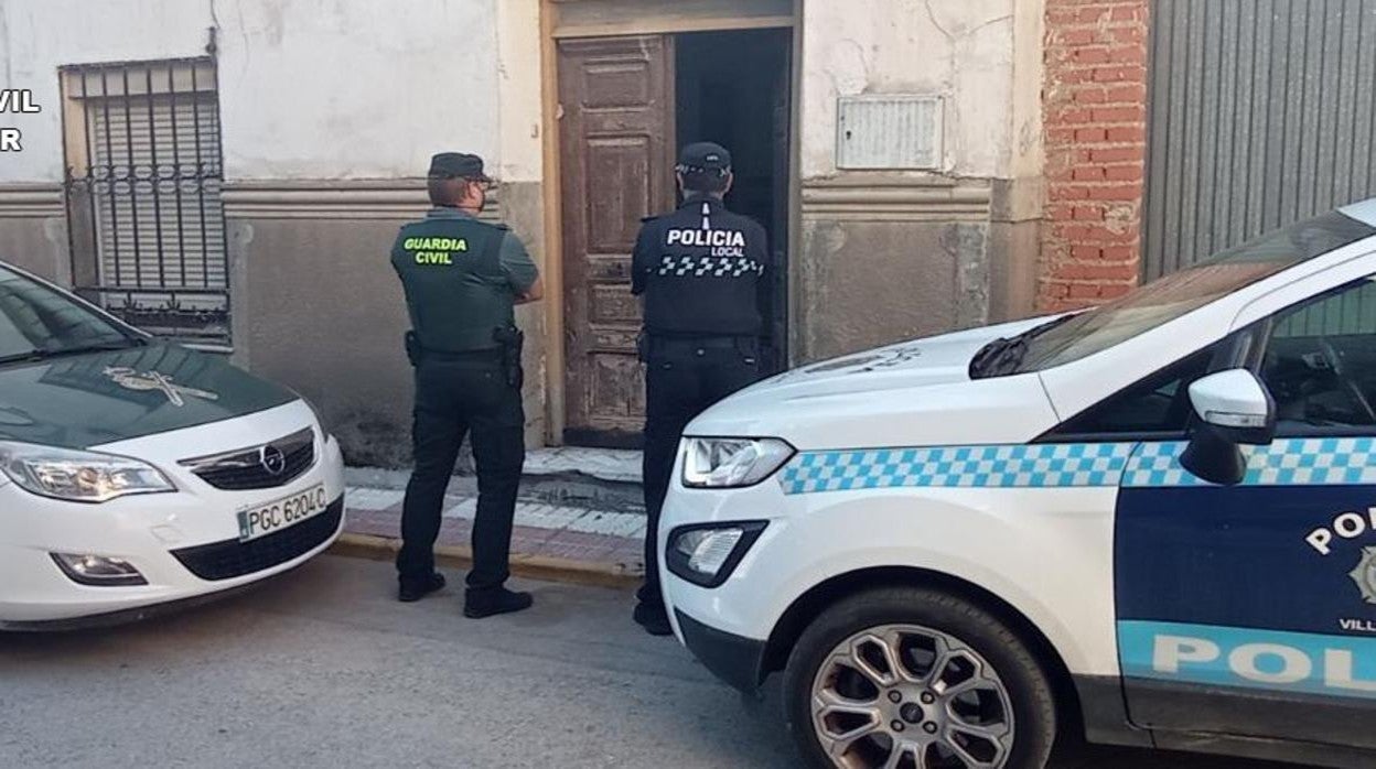 Dos agentes de ambos cuerpos ante la puerta de la vivienda