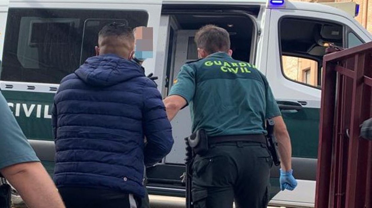 Uno de los detenidos es conducido al furgón de la Guardia Civil