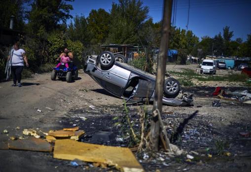 Un coche volcado y completamente abandonado junto a la orilla del río Guadarrama