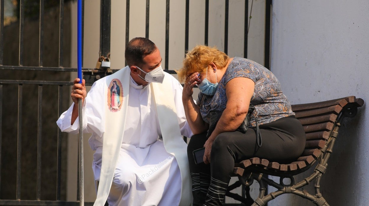 El párroco Alberto Hernández, que limpiaba cenizas, atiende a una vecina