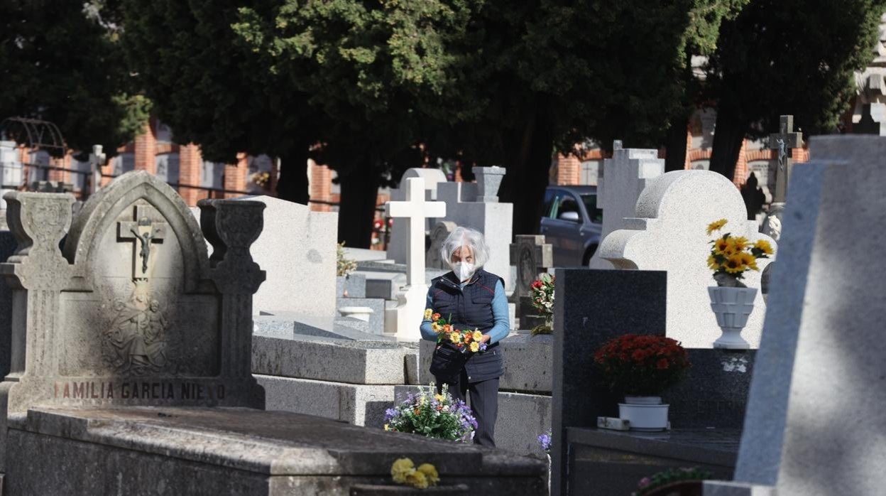 Una anciana lleva flores a la tumba de un familiar