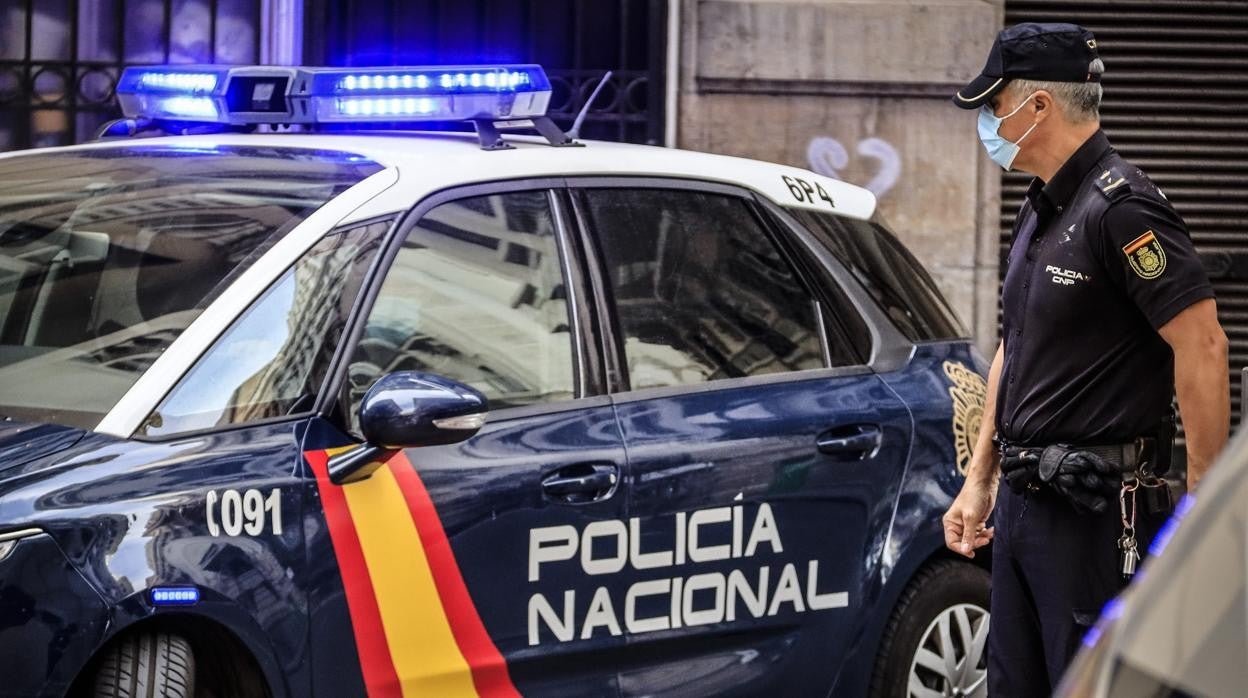 Imagen de archivo de un agente de la Policía Nacional junto a su coche patrulla en la Comunidad Valenciana